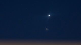 two bright planets in the night sky. one is surrounded by a few bright points of light