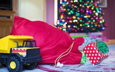Red Santa christmas sacks next to a toy truck and by a Christmas tree