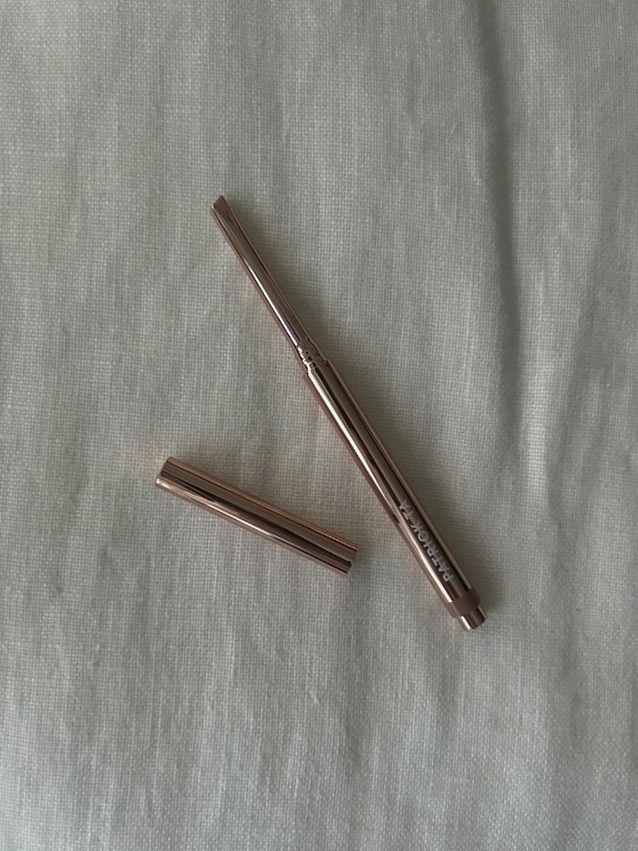 PATRICK TA Monochrome Moment Precision Lip Crayon on a white linen background