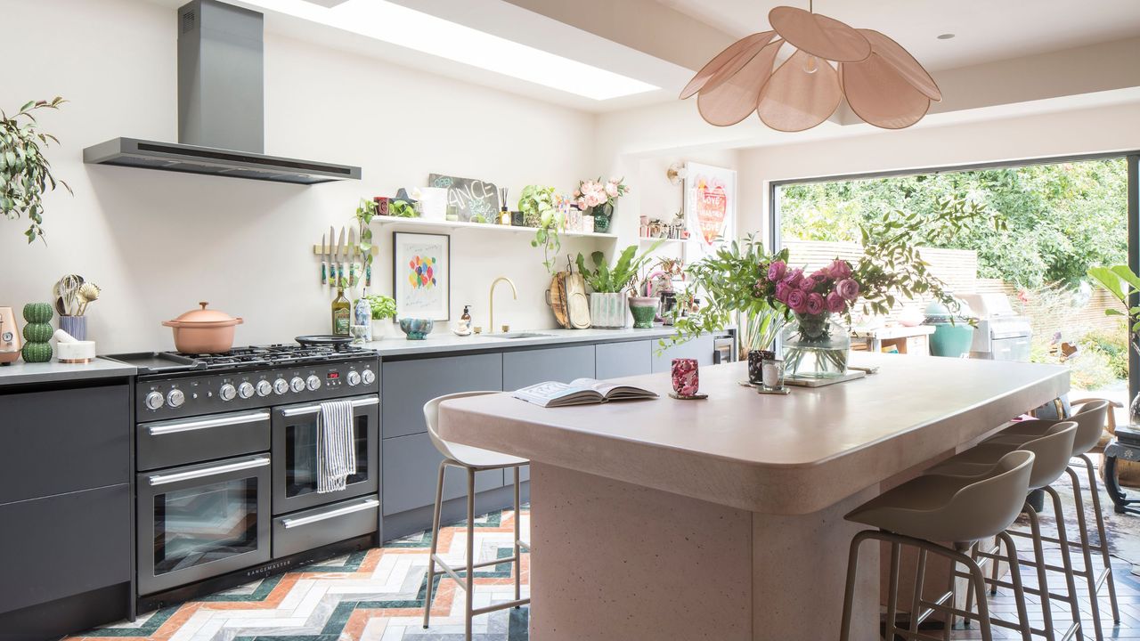 kitchen extension with colourful marble chevron flooring and pink concrete island and dark blue cabinetry 