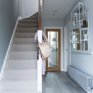 Mirror mounted on grey wall next to white staircase with grey stair case carpet