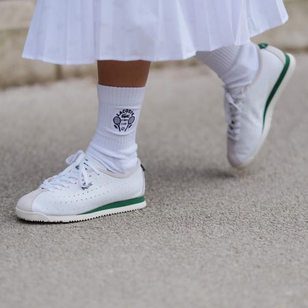 A guest wears white socks, white sneaker shoes, outside Lacoste, during the Paris Fashion week Women's Fall/Winter 2025-2026 on March 9, 2025 in Paris, France. 