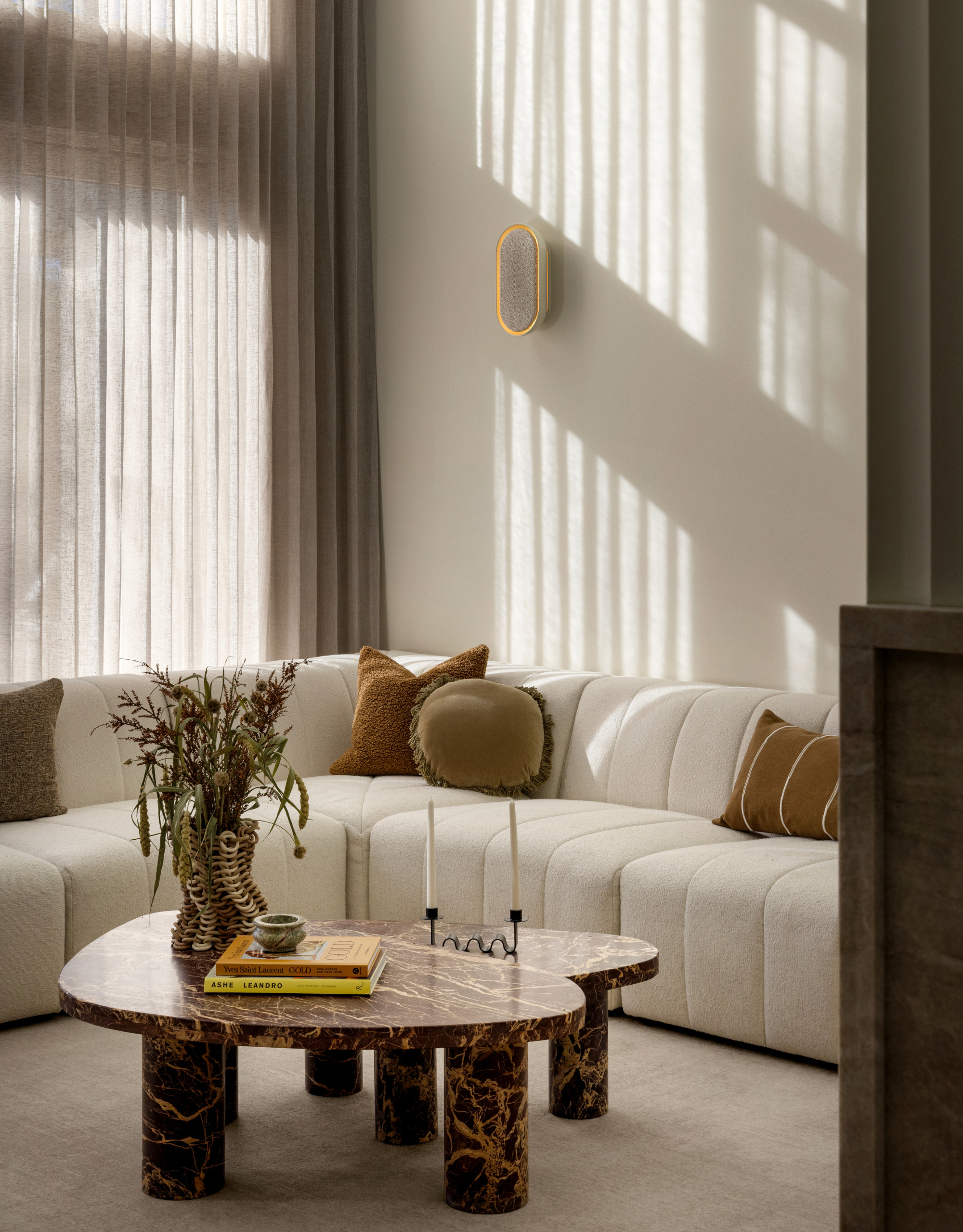 A white living room with a white l-couch and a pair of marble coffee tables