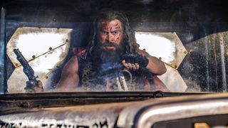 Dementus conduce enojado su auto con su pistola en la mano derecha en Furiosa: A Mad Max Saga