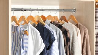 Wooden hangers holding clothes in a closet