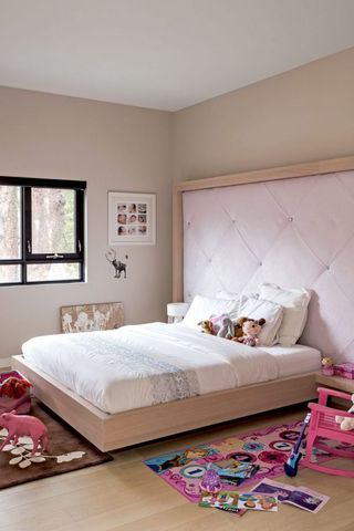 Pink girls bedroom idea with large upholstered pink headboard
