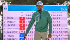 Marco Penge walks on the green with a scoreboard behind him