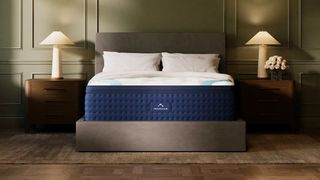 Image shows the DreamCloud Premier Hybrid Mattress which we reviewed on a tall grey fabric bed frame in 