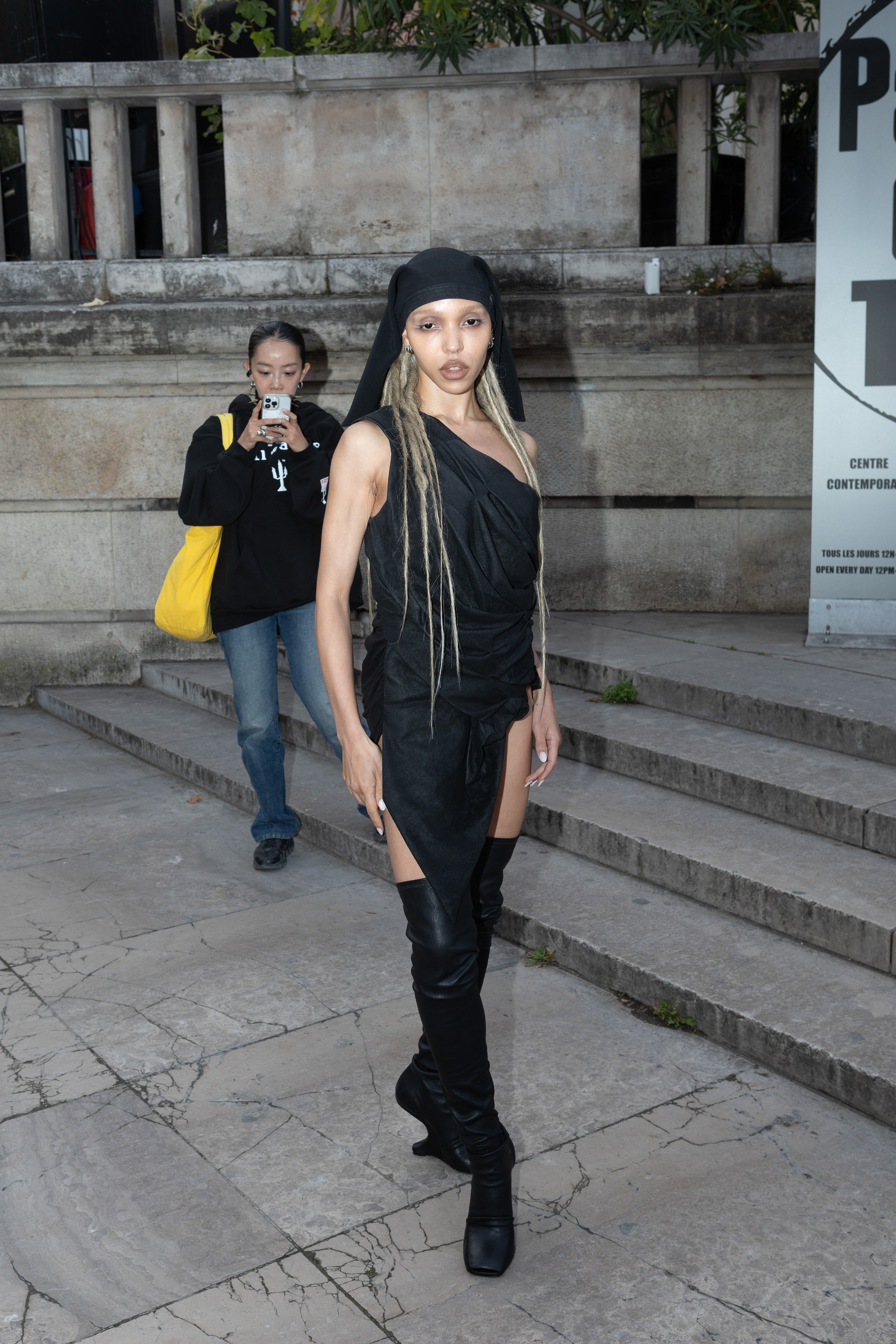FKA twigs wearing faux locs, a black wrap dress and knee high boots.