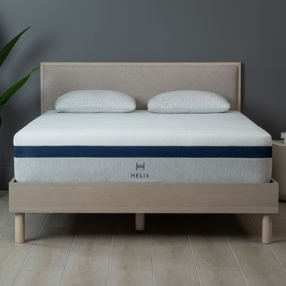 The Helix Midnight mattress for side sleepers placed on a light wooden and fabric bed frame in a grey bedroom