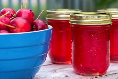 Two jars of crab apple jelly and a bowl of crab apples