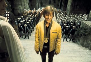 a young man in a gold jacket in a crowded throne room