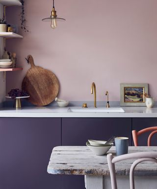 purple painted kitchen cabinets with white worktop and pink wall