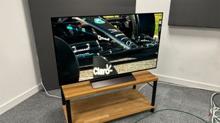 LG C4 (OLED48C4) 48-inch TV slight top-down angle on wooden TV bench with F1 car on screen