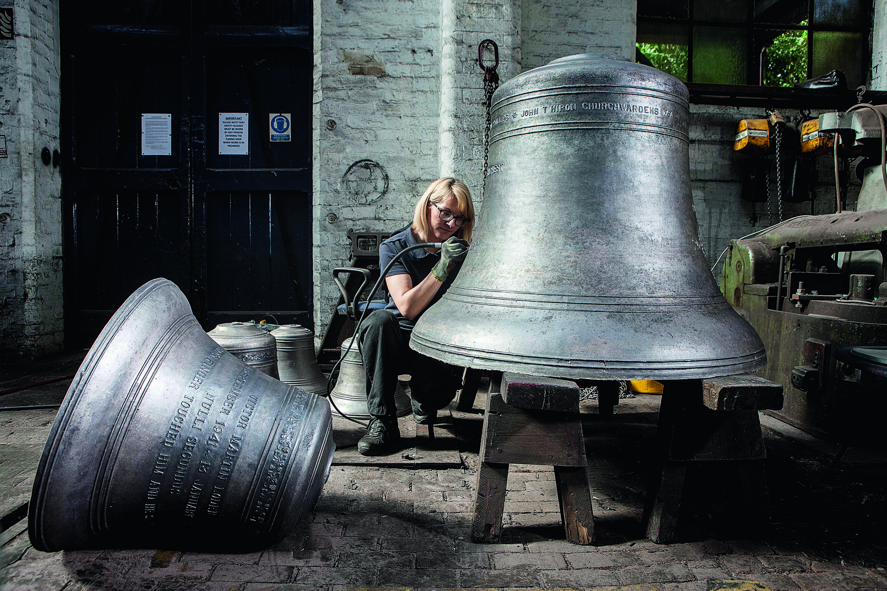 A worker at John Taylor &amp; Co works on engraving a gigantic bell