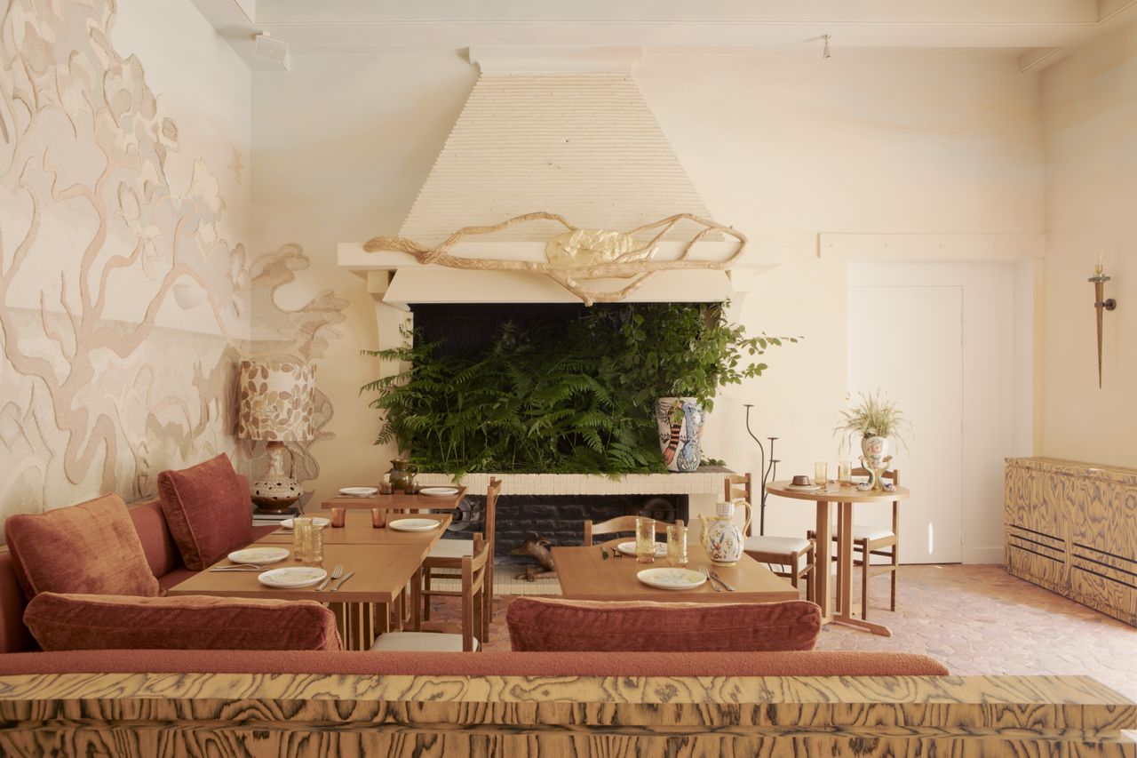 A whimsically designed hotel boasts richly layered interiors characterized by hand-drawn, fantastical mural motifs, earthy and pastel shades, and shapely furniture.