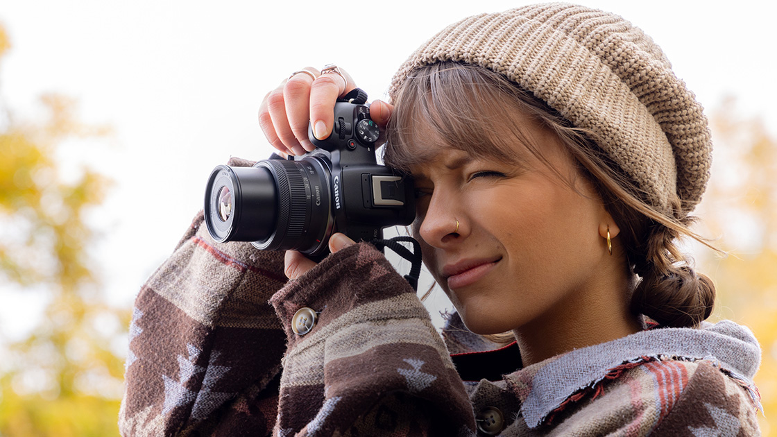Lifestyle image of person looking through camera viewfinder 