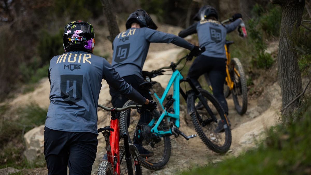 YT MOB team pushing their new mountain bikes uphill