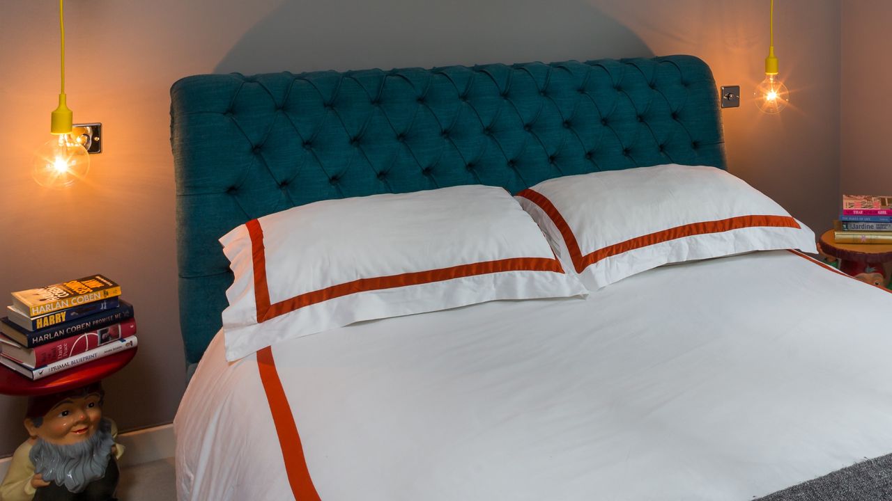 A bed with a quilted eheadboard and pendant lights on either side