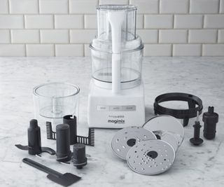 Magimix food processor on a wooden countertop with a wipe beside it
