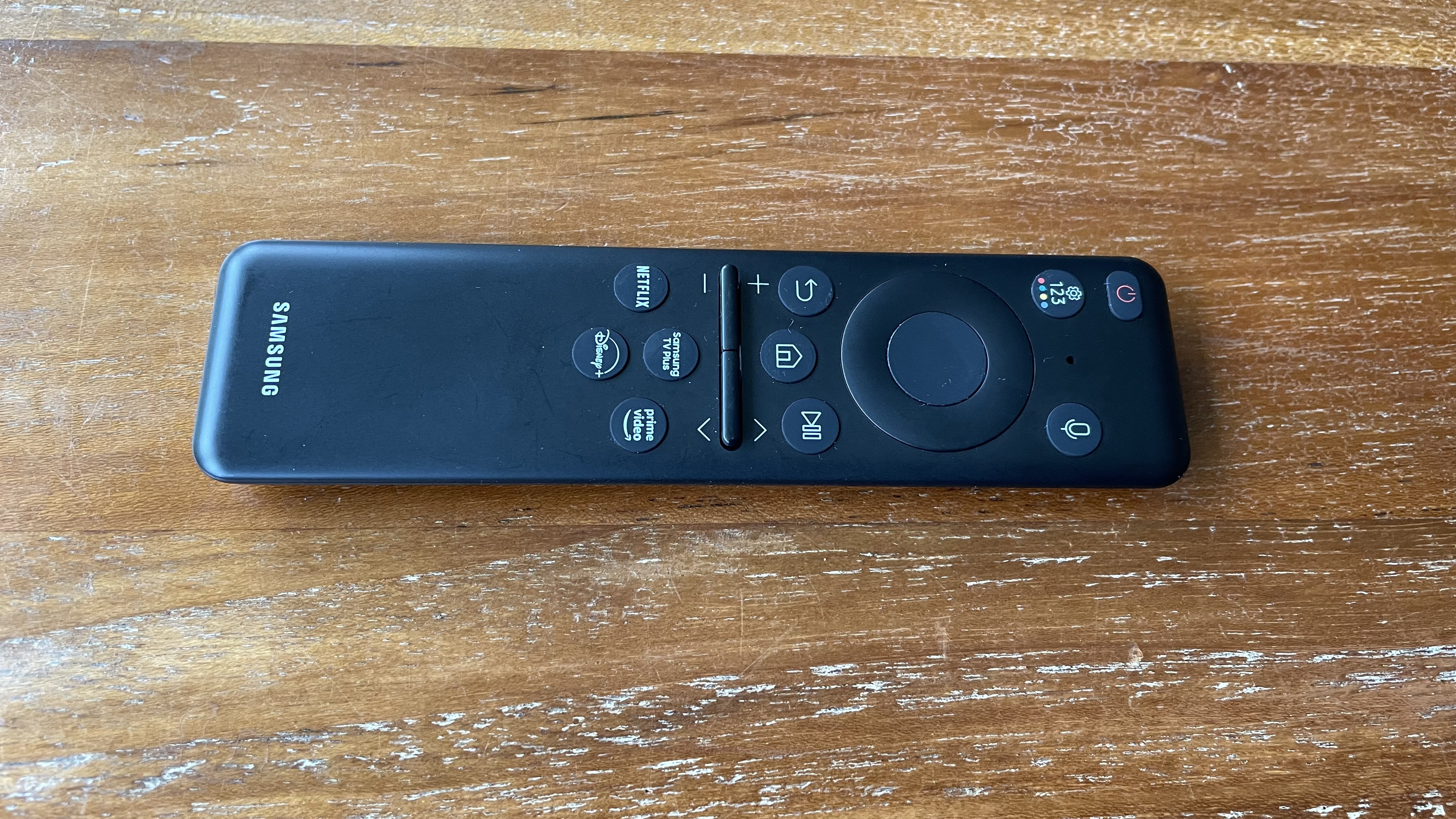 Samsung S95C OLED TV remote control on stand