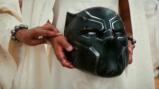 Hands holding the Black Panther mask in Black Panther: Wakanda Forever
