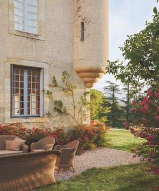 French house exterior with lawn, climbing plant, roses, outdoor furniture