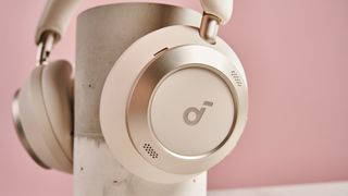 The earcups of the Anker Soundcore Space One Pro resting on a concrete pillar in front of a pink wall