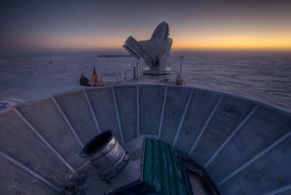 The sun sets behind BICEP2 (in the foreground) and the South Pole Telescope (in the background).
