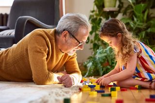 a grandfather plays blocks with granddaughter