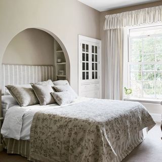 bedroom with cream wall curtains on window and pillows on bed