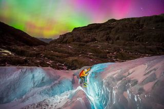 A photograph of the northern lights overn an ice climber