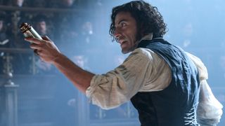 Oscar Isaac points a scroll at a crowd 