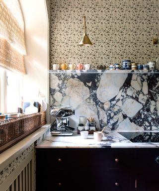 floral wallpapered kitchen with a dark viola marble countertop and backsplash that meets the wallpaper halfway up the wall