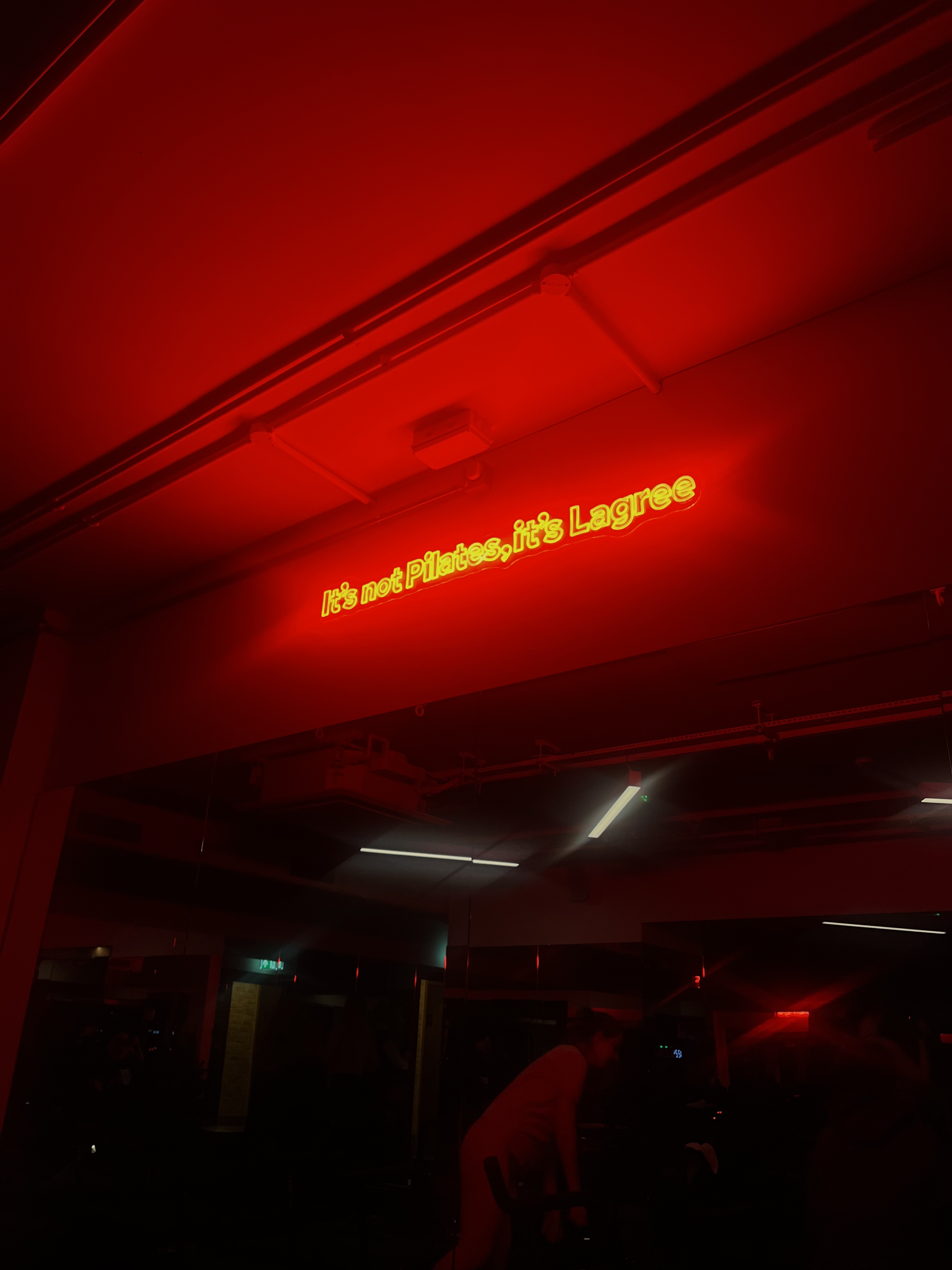 A neon red sign in a Lagree studio