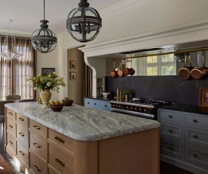 A traditional kitchen with a wooden island, blue cabinets, and a mirrored backsplash