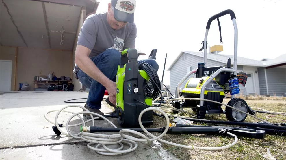 A man in a baseball cap with the Greenworks GPW1501 unit stood next to the RYOBI RY1422
