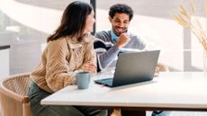 Young smiling couple calculating their finances at home on their laptop 
