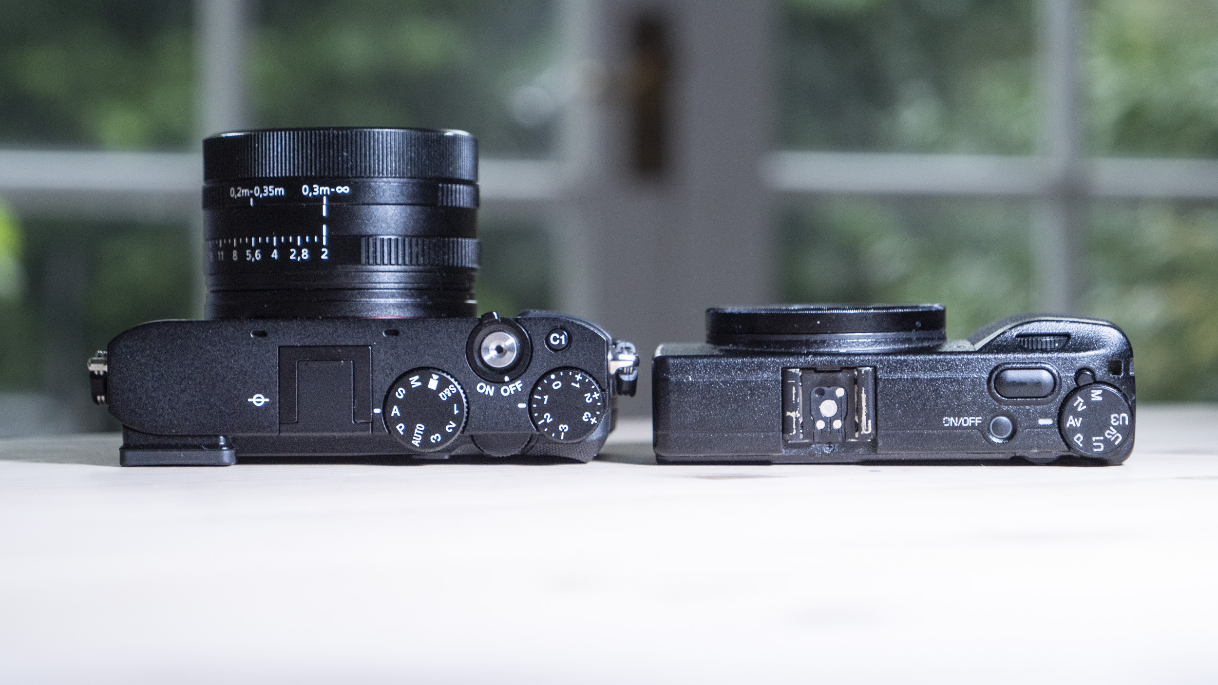 Sony RX1R III compact camera alongside the Ricoh GR IIIx, on a wooden table
