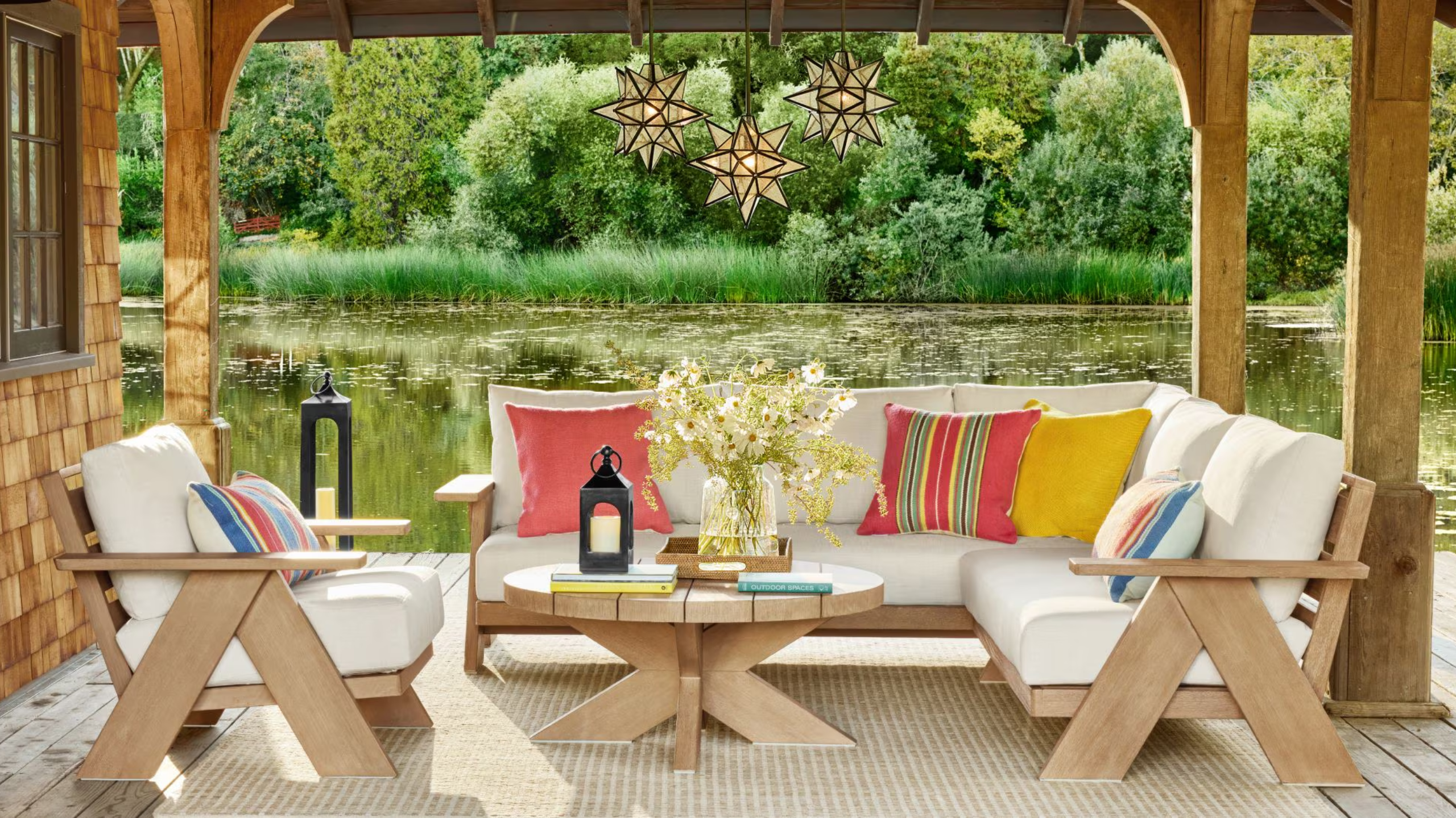 a porch with a sectional, an accent chair, and a round table overlooking a lake