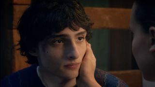 Finn Wolfhard's Mike Wheeler being comforted, hand on his face, by Eleven.