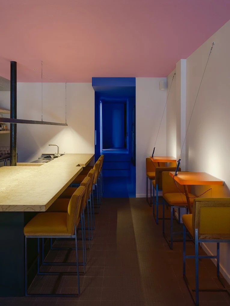 The exterior and interior of a blue and pink-tinted bar.