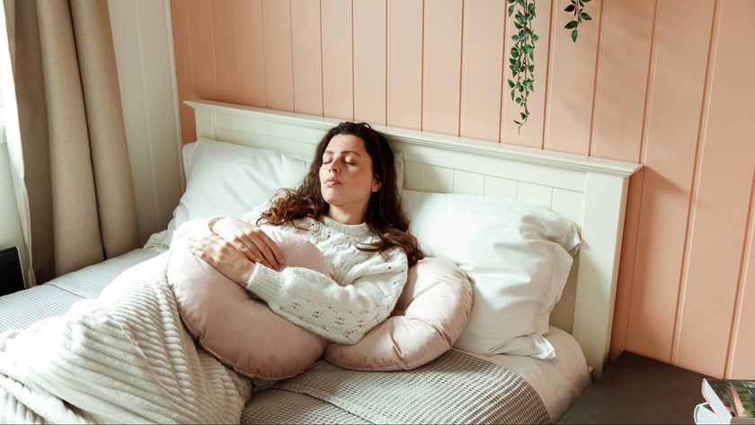 A woman lying on her bed with extra pillows around her for support