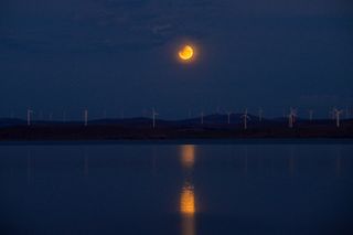 total lunar eclipse reflected in water below.