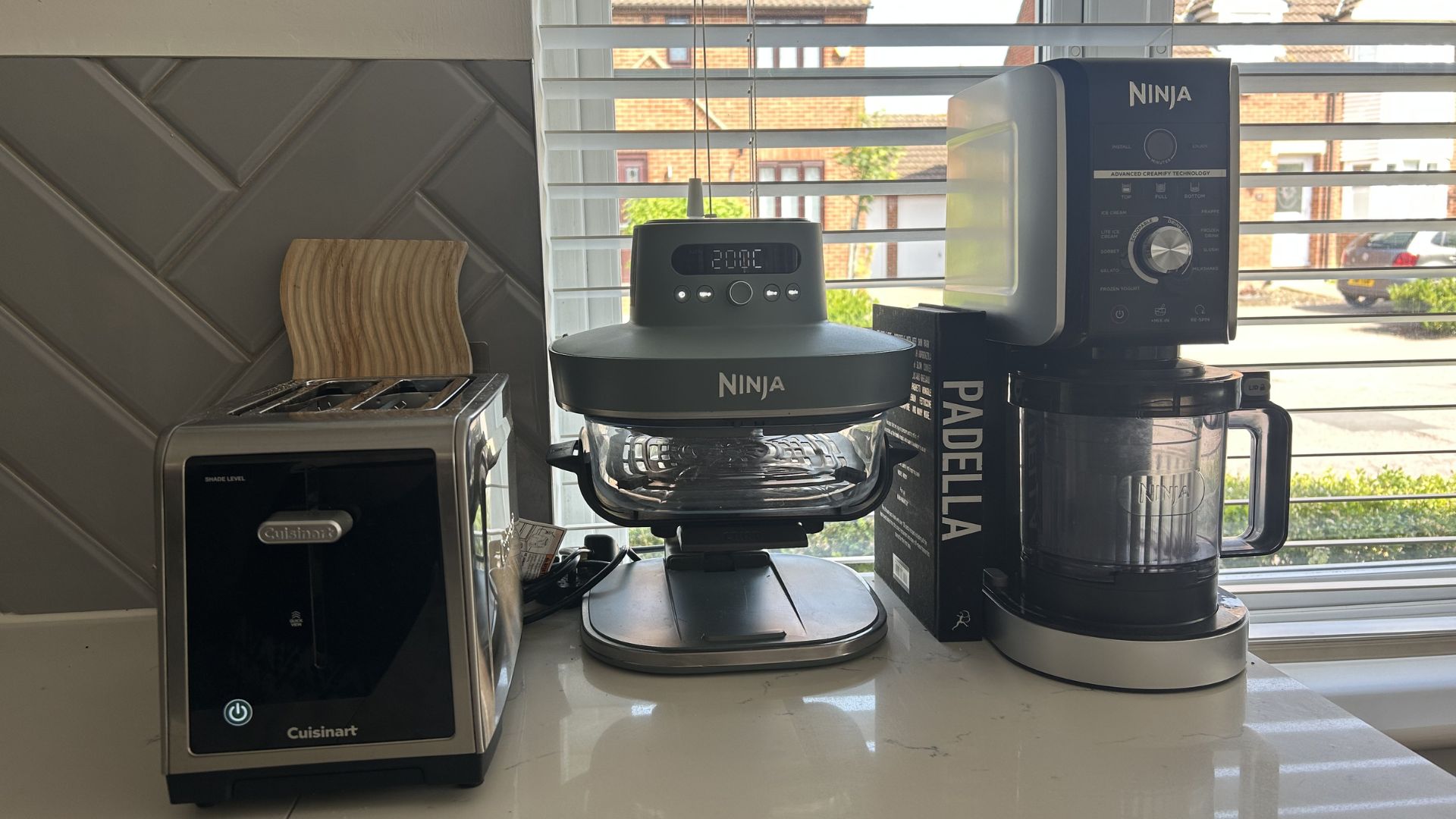 Kitchen appliances x 3 on worktop with blinds behind