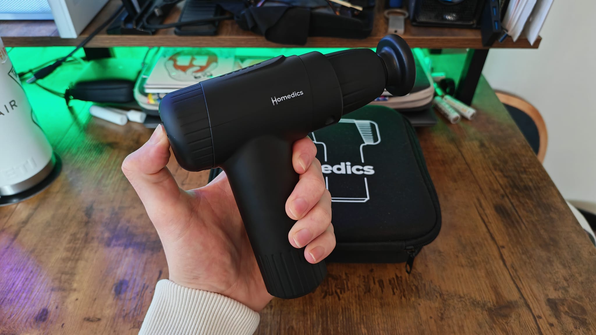 A reviewer holding the Homedics Novo massage gun