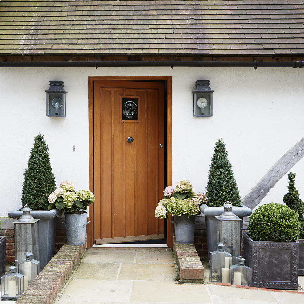 house with white wall and wooden door and plants