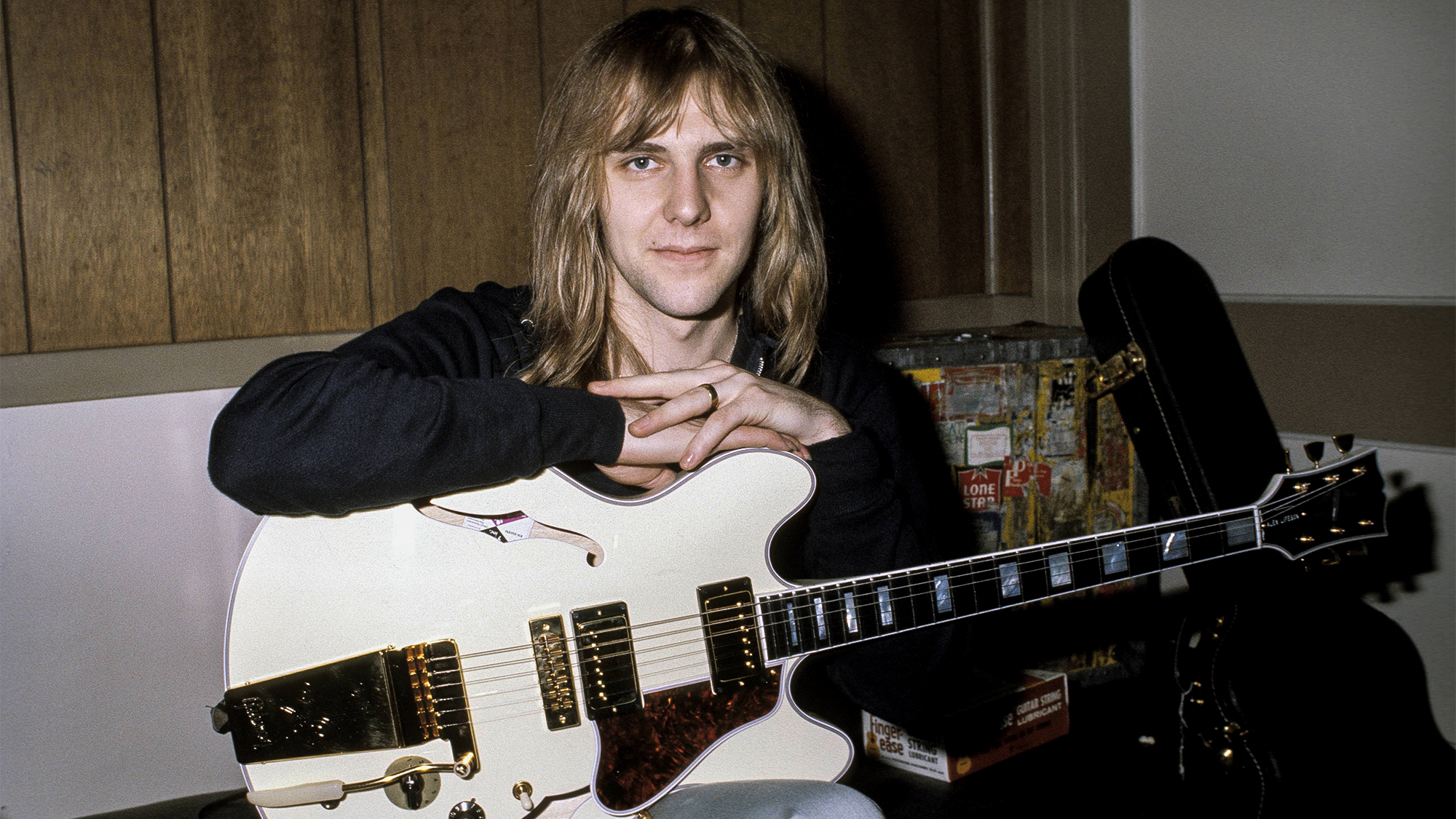 Alex Lifeson, posed, backstage, holding his 1976 "Whitey" Gibson ES-355 guitar 