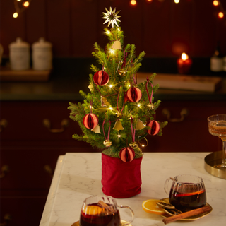 mini christmas tree with baubles and bells in kitchen with mulled wine