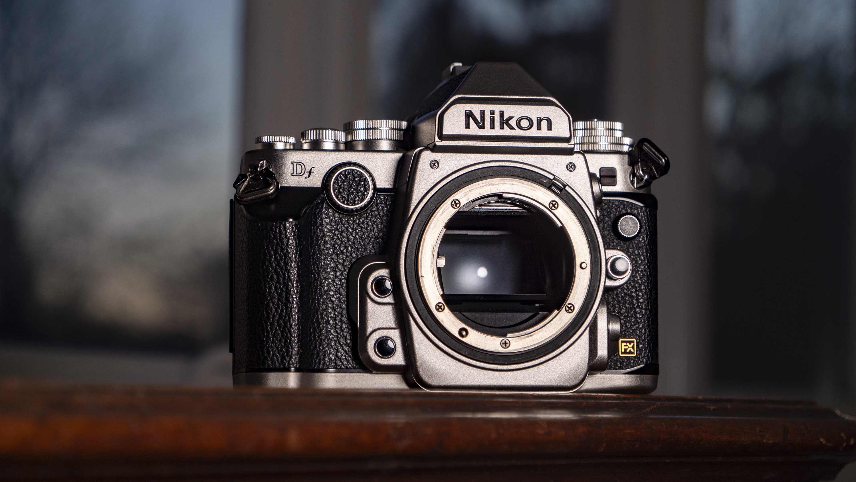 Nikon Df DSLR camera on a wooden surface by large window, with dusk light